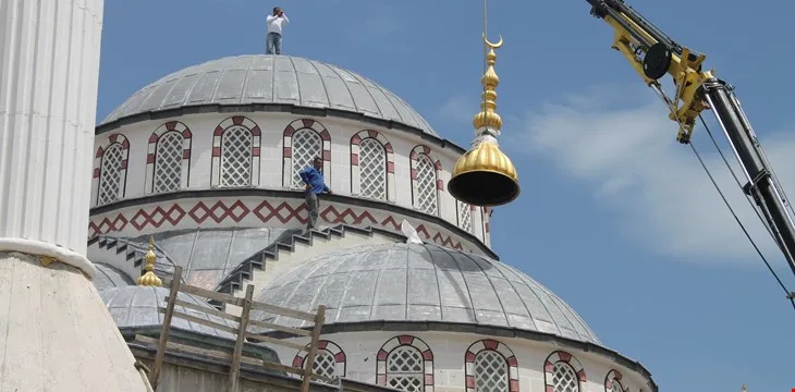 Construction of the mosque with the dome mounted by crane